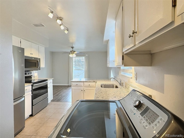 kitchen with appliances with stainless steel finishes, white cabinetry, sink, kitchen peninsula, and a healthy amount of sunlight