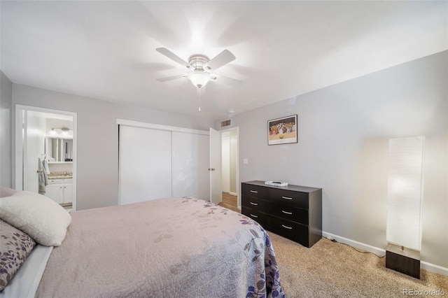 bedroom featuring ensuite bathroom, light carpet, ceiling fan, and a closet