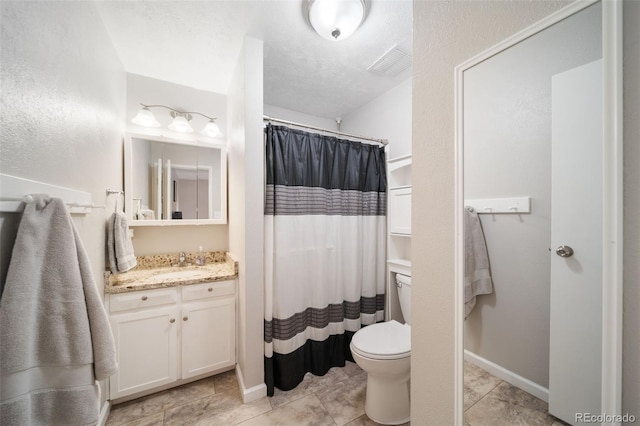 bathroom with tile patterned floors, vanity, toilet, and a textured ceiling