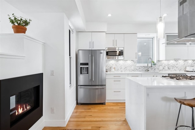 kitchen with white cabinetry, wall chimney range hood, sink, and appliances with stainless steel finishes