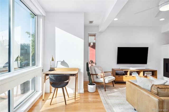 living room with beamed ceiling, ceiling fan, and light wood-type flooring