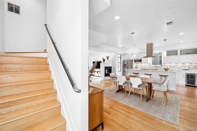 dining space with wine cooler and light wood-type flooring