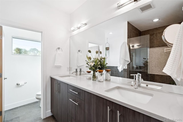 bathroom with vanity, toilet, and tiled shower