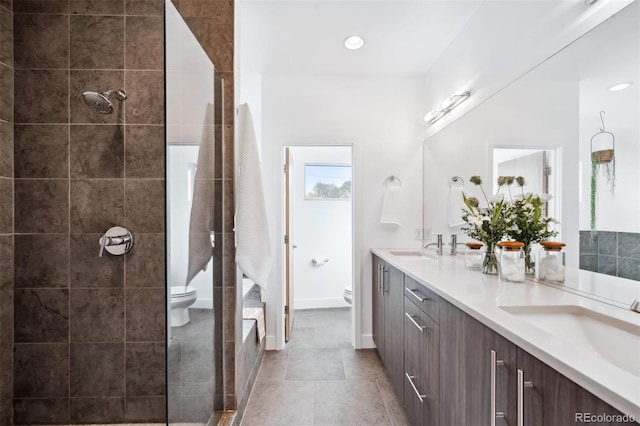 bathroom with tile patterned floors, vanity, toilet, and a tile shower