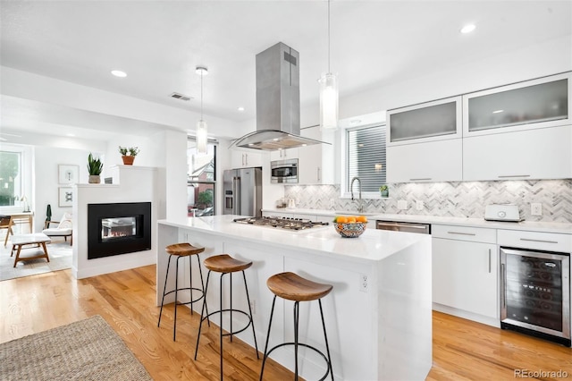 kitchen with hanging light fixtures, island range hood, beverage cooler, and a center island