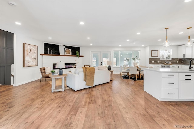 living room featuring sink, a large fireplace, and light wood-type flooring