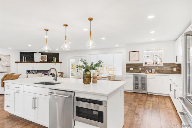 kitchen featuring decorative light fixtures, white cabinetry, sink, and wine cooler