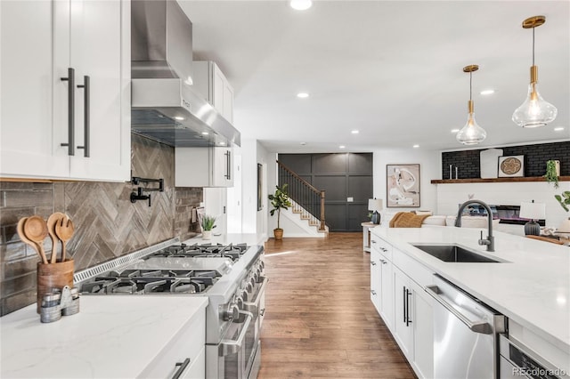 kitchen with appliances with stainless steel finishes, tasteful backsplash, wall chimney range hood, sink, and white cabinetry