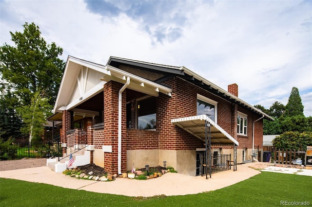 view of property exterior with a yard, a chimney, fence, and brick siding