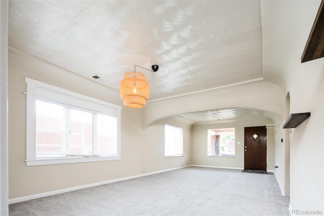 carpeted entryway featuring arched walkways, visible vents, and baseboards