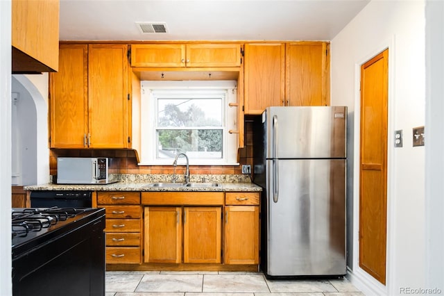 kitchen featuring stainless steel appliances, a sink, visible vents, and brown cabinets