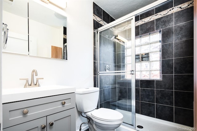 bathroom with toilet, a shower stall, vanity, and a textured ceiling