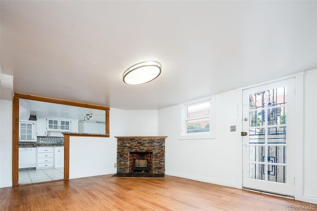 unfurnished living room featuring light wood-style flooring, a fireplace, and baseboards