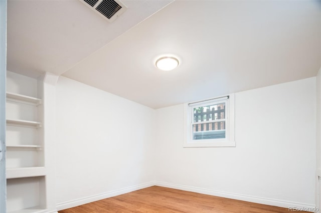 empty room featuring visible vents, light wood-style flooring, and baseboards