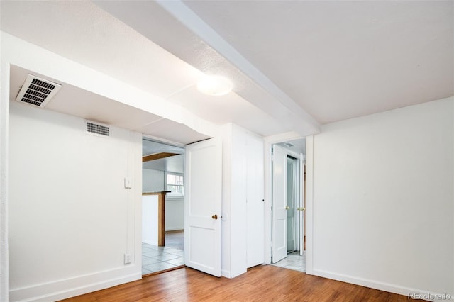 spare room featuring light wood-style floors, visible vents, and baseboards