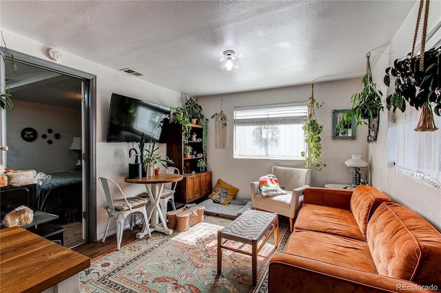 living room with visible vents, a textured ceiling, and wood finished floors