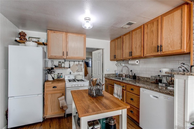 kitchen with white appliances, tasteful backsplash, visible vents, dark wood-style flooring, and a sink