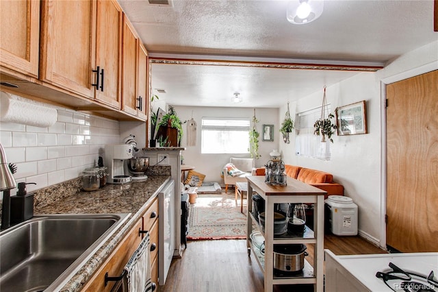 kitchen featuring brown cabinets, backsplash, wood finished floors, a textured ceiling, and a sink