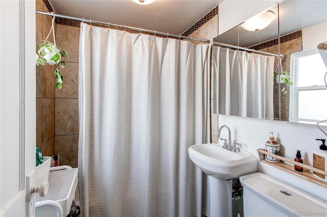 full bath with toilet, a shower with curtain, and a sink