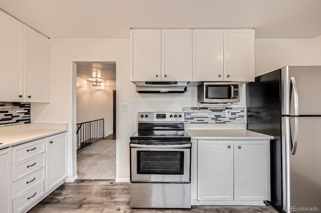 1207 Kingsley Dr, Colorado Springs, CO 80909 - kitchen with under cabinet range hood, stainless steel appliances, and white cabinetry