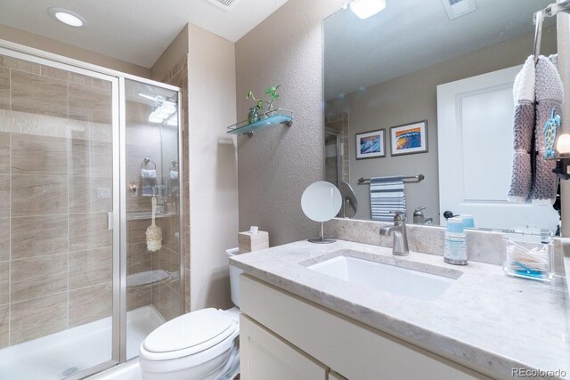 565 Pikes View Dr, Erie, CO 80516 - bathroom featuring vanity, toilet, a textured wall, and a stall shower