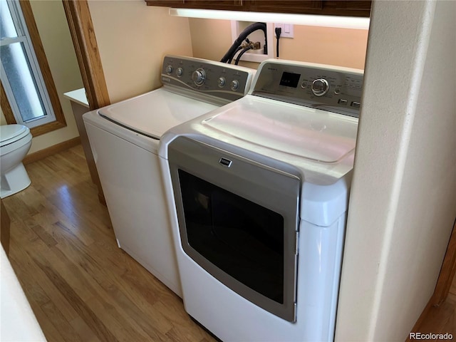 laundry room with washing machine and dryer and light wood-type flooring