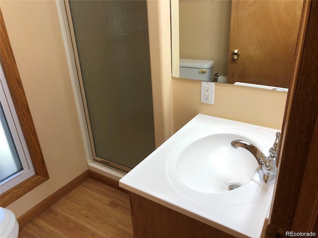 bathroom with hardwood / wood-style floors, vanity, toilet, and a shower with shower door