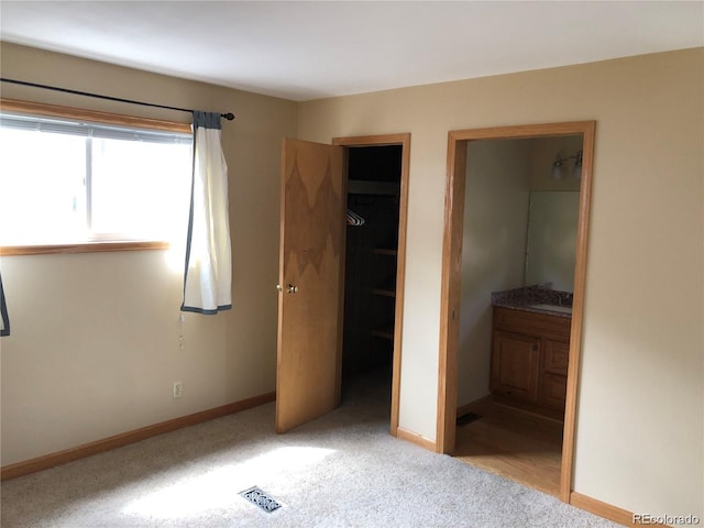 unfurnished bedroom featuring light carpet, ensuite bath, and sink