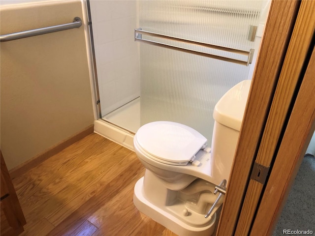 bathroom with hardwood / wood-style floors, an enclosed shower, and toilet