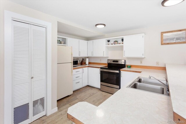 kitchen with stainless steel appliances, open shelves, light countertops, and white cabinetry