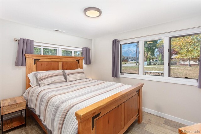 bedroom with multiple windows, wood finished floors, visible vents, and baseboards