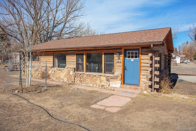 view of front of property featuring stone siding, roof with shingles, and log siding