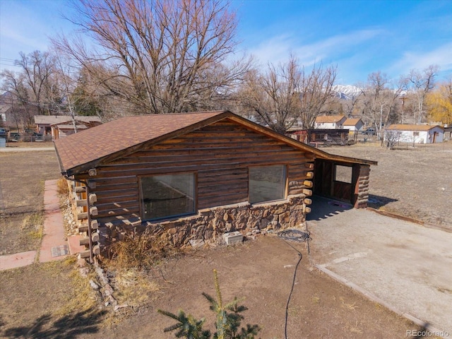 view of side of property featuring a shingled roof and log exterior