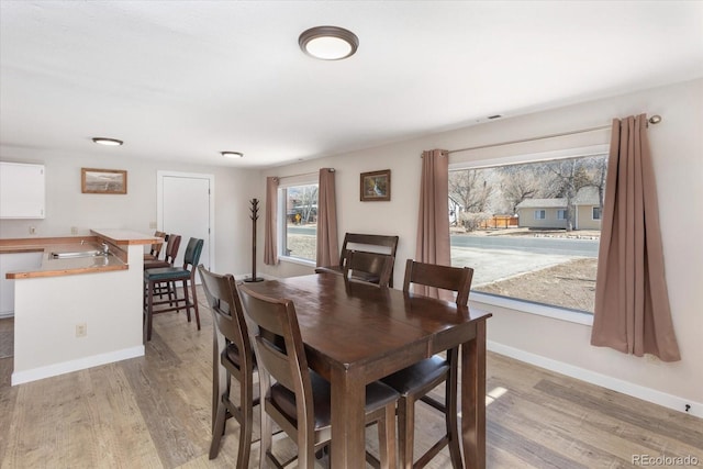 dining space with light wood-type flooring, visible vents, and baseboards