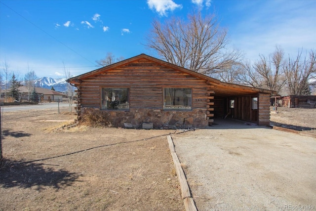 exterior space featuring log exterior, driveway, an attached carport, and a mountain view