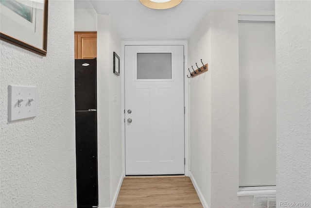 14934 E Hampden Cir Unit 3, Aurora, CO 80014 - doorway to outside featuring light wood-style floors and a textured wall