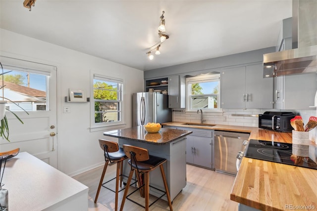 2430 N Tejon St, Colorado Springs, CO 80907 - kitchen with appliances with stainless steel finishes, wall chimney range hood, a sink, a kitchen island, and butcher block countertops