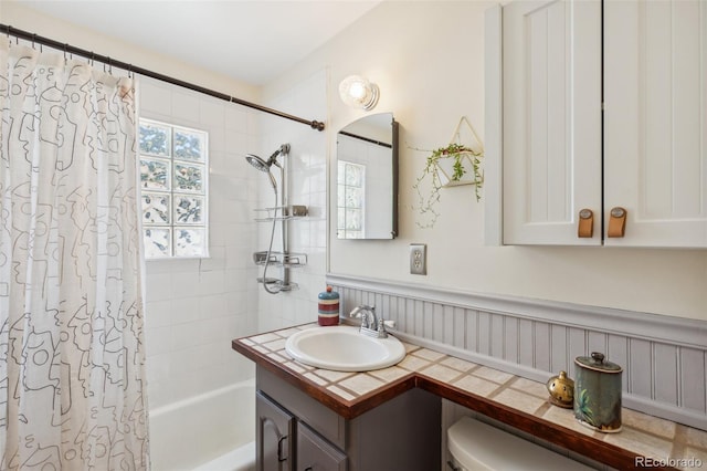 2430 N Tejon St, Colorado Springs, CO 80907 - bathroom with shower / bath combination with curtain, vanity, a wainscoted wall, and toilet