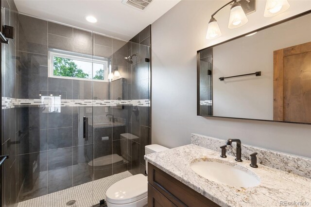 bathroom featuring a shower with door, vanity, and toilet