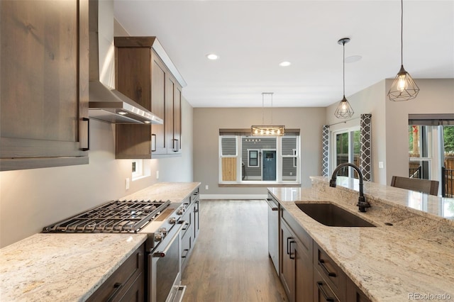 kitchen featuring pendant lighting, sink, wall chimney range hood, and appliances with stainless steel finishes