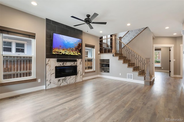 unfurnished living room with hardwood / wood-style flooring, ceiling fan, and a high end fireplace