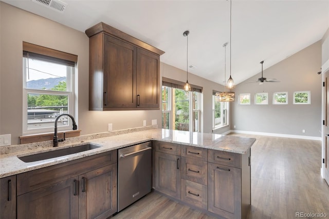 kitchen featuring sink, light stone counters, hanging light fixtures, stainless steel dishwasher, and plenty of natural light