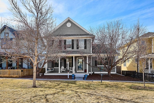 view of front of house with covered porch, a front yard, and fence