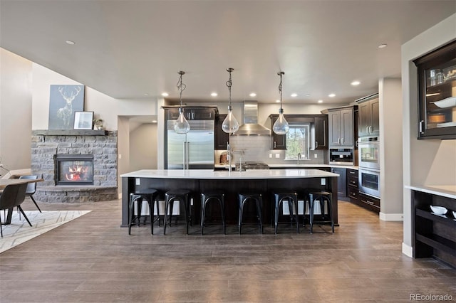 1803 Avenida Del Sol, Castle Rock, CO 80104 - kitchen with wall chimney range hood, appliances with stainless steel finishes, light countertops, a large island with sink, and recessed lighting