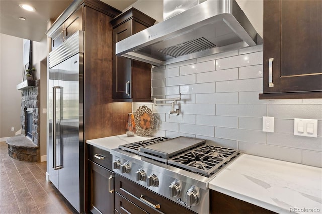 1803 Avenida Del Sol, Castle Rock, CO 80104 - kitchen with stainless steel appliances, exhaust hood, backsplash, dark wood-style flooring, and dark brown cabinetry