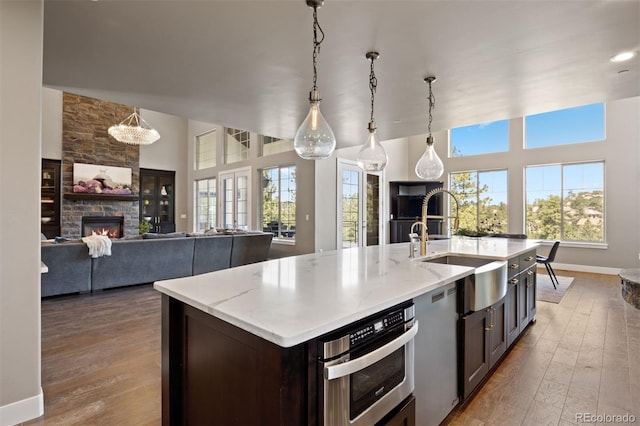 1803 Avenida Del Sol, Castle Rock, CO 80104 - kitchen with plenty of natural light, a stone fireplace, wood finished floors, and a center island with sink