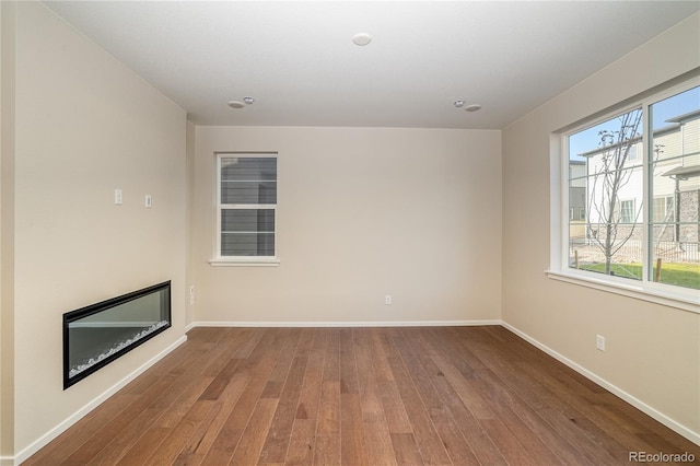 23931 E 40th Ave, Aurora, CO 80019 - unfurnished living room featuring wood-type flooring and a glass covered fireplace