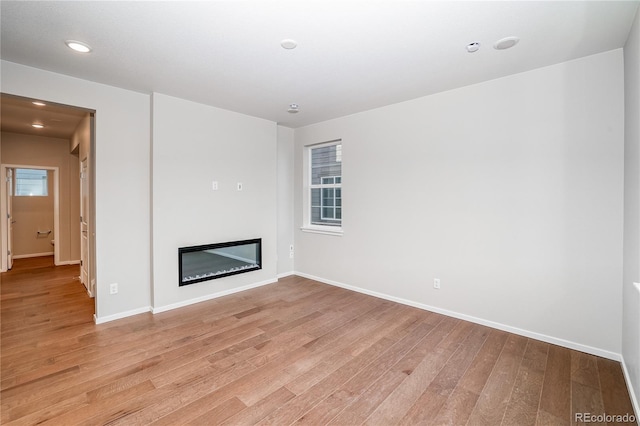 23931 E 40th Ave, Aurora, CO 80019 - unfurnished living room featuring light wood finished floors, a glass covered fireplace, and recessed lighting