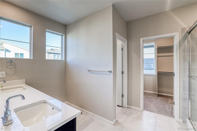 23931 E 40th Ave, Aurora, CO 80019 - full bathroom featuring double vanity, tiled shower, a spacious closet, and tile patterned floors