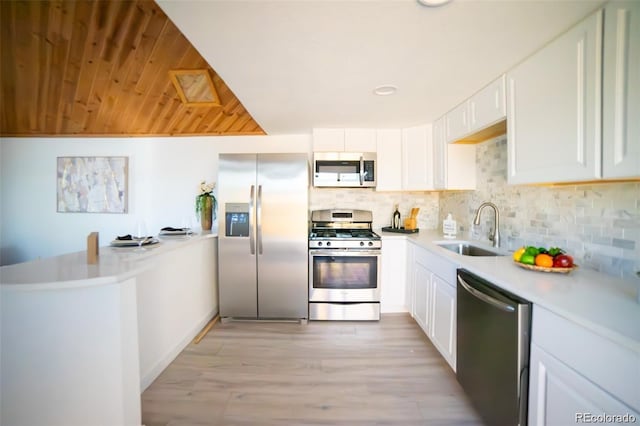 kitchen featuring a peninsula, appliances with stainless steel finishes, decorative backsplash, and a sink